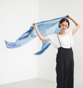 絣染めシルクコットンショール　ブルー　手にもってなびく様子の画像